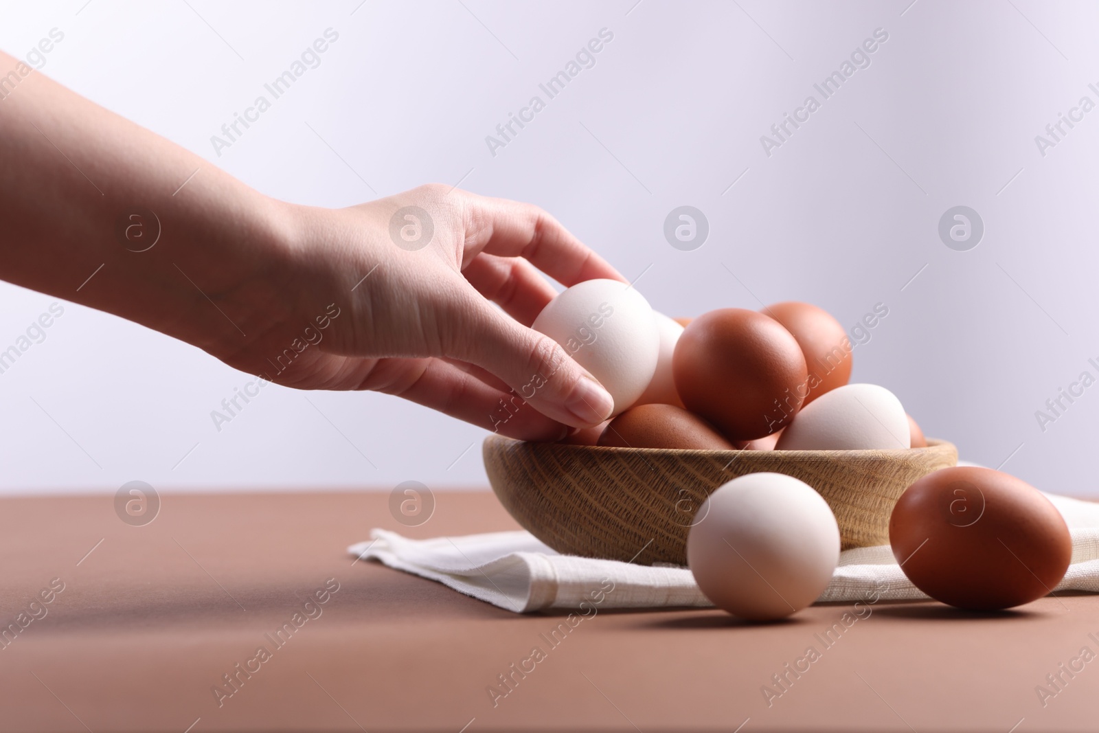 Photo of Woman with raw eggs at brown table, closeup