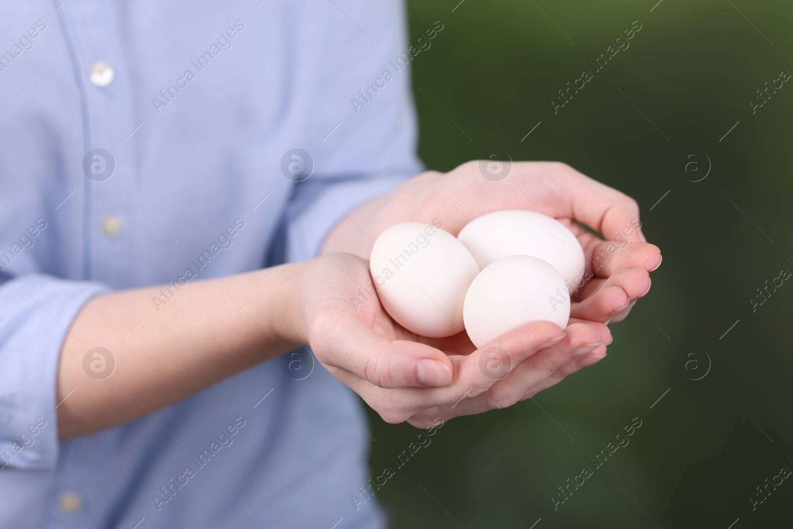 Photo of Woman with raw eggs on blurred background, closeup