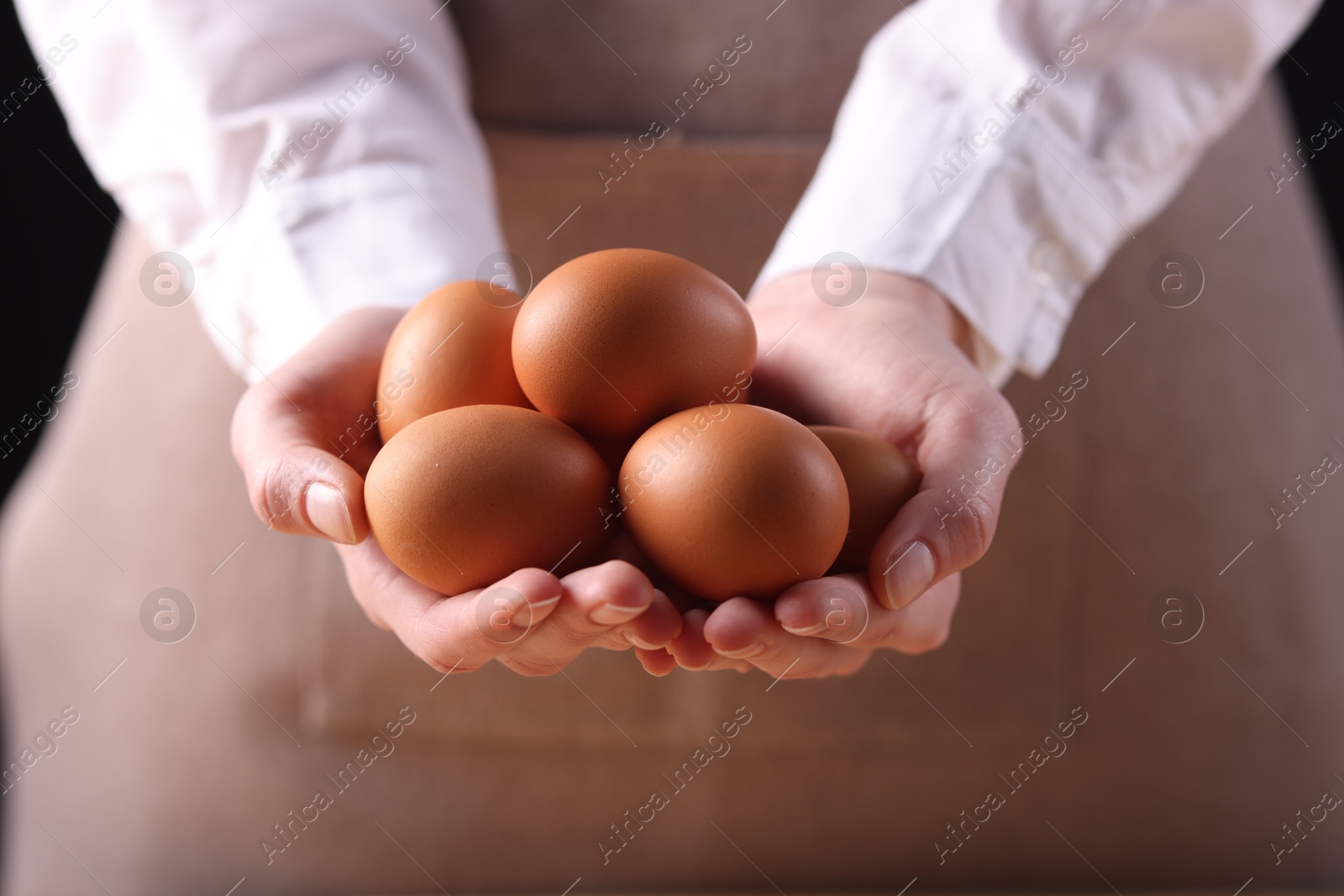 Photo of Woman with raw eggs on dark background, closeup