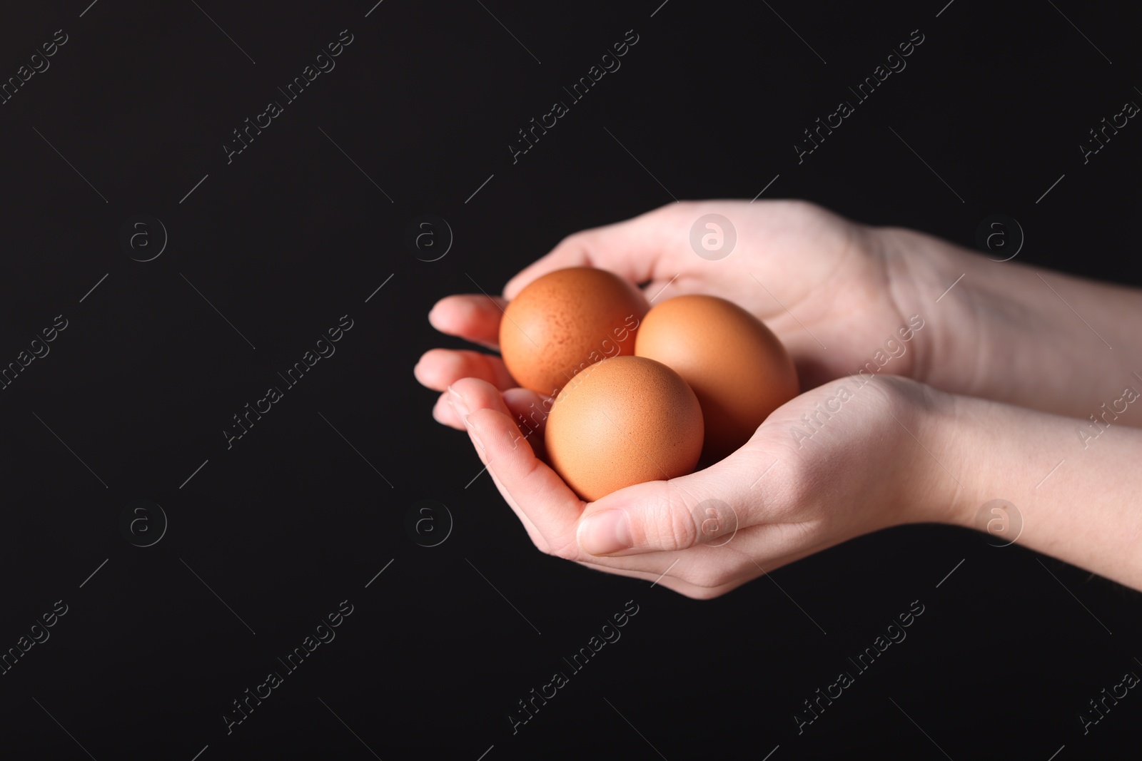 Photo of Woman with raw eggs on black background, closeup. Space for text