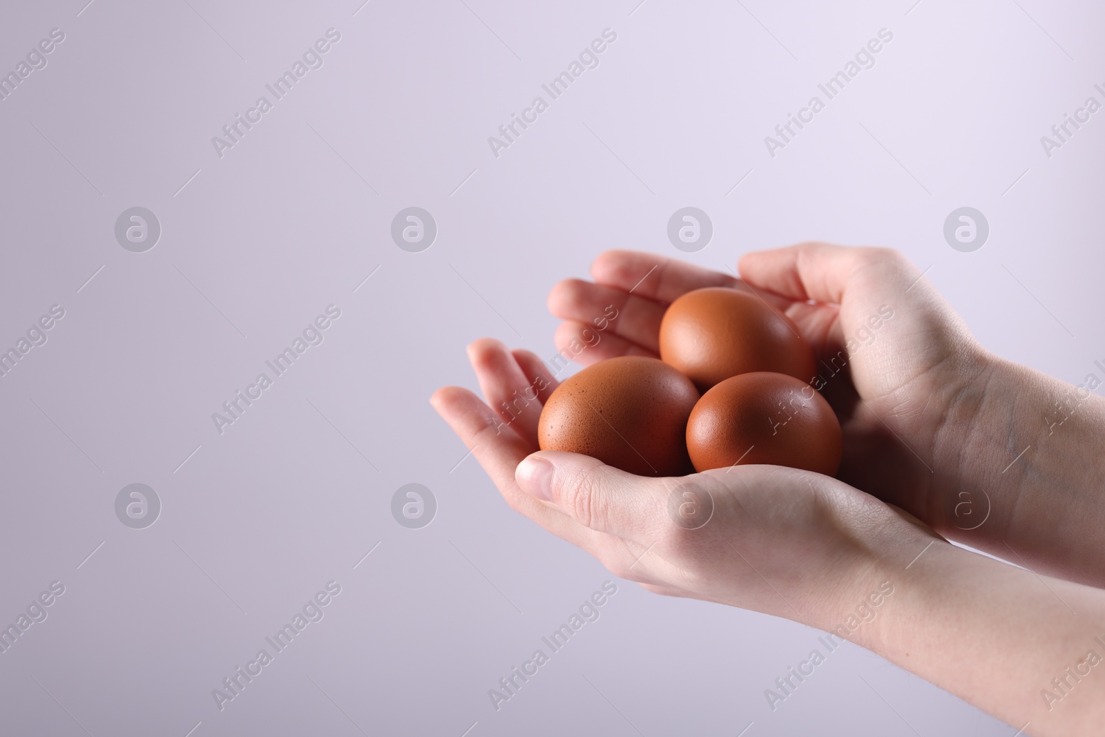 Photo of Woman with raw eggs on light background, closeup. Space for text