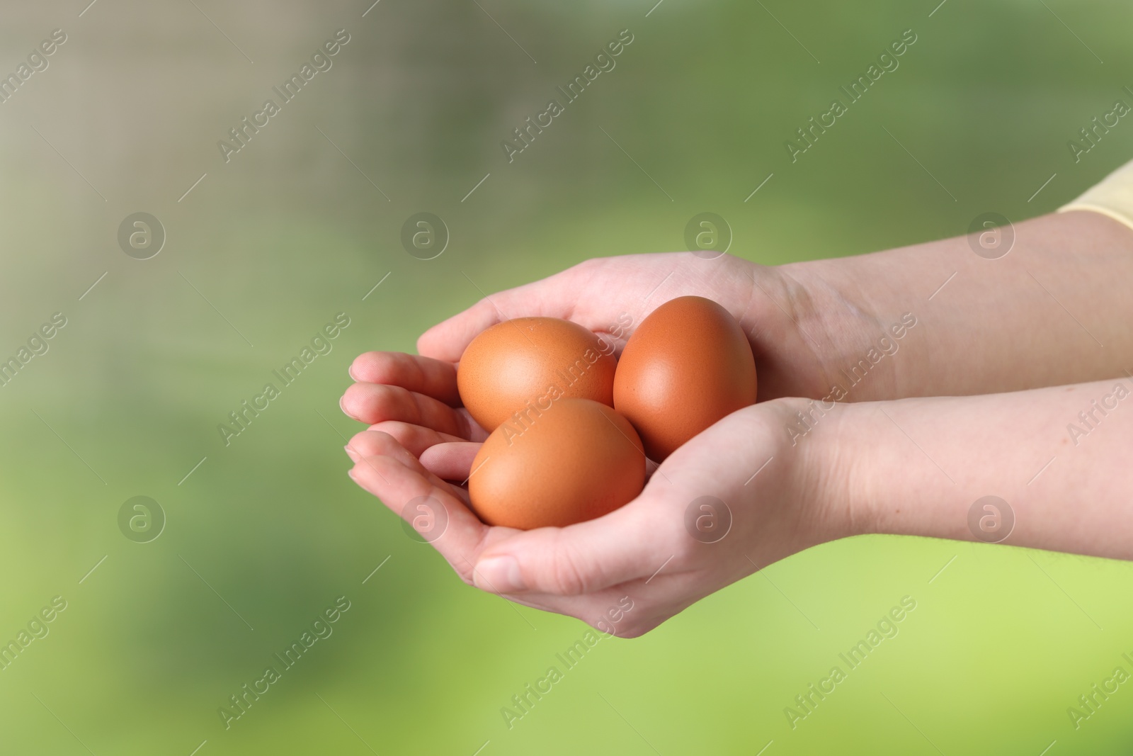 Photo of Woman with raw eggs on blurred background, closeup