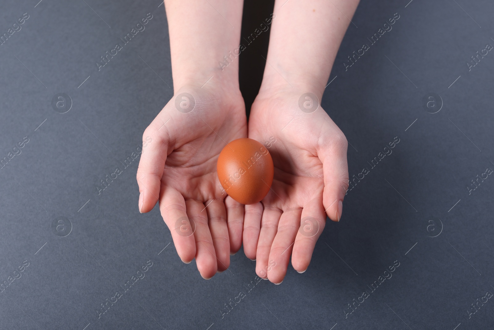 Photo of Woman with raw egg on grey background, top view