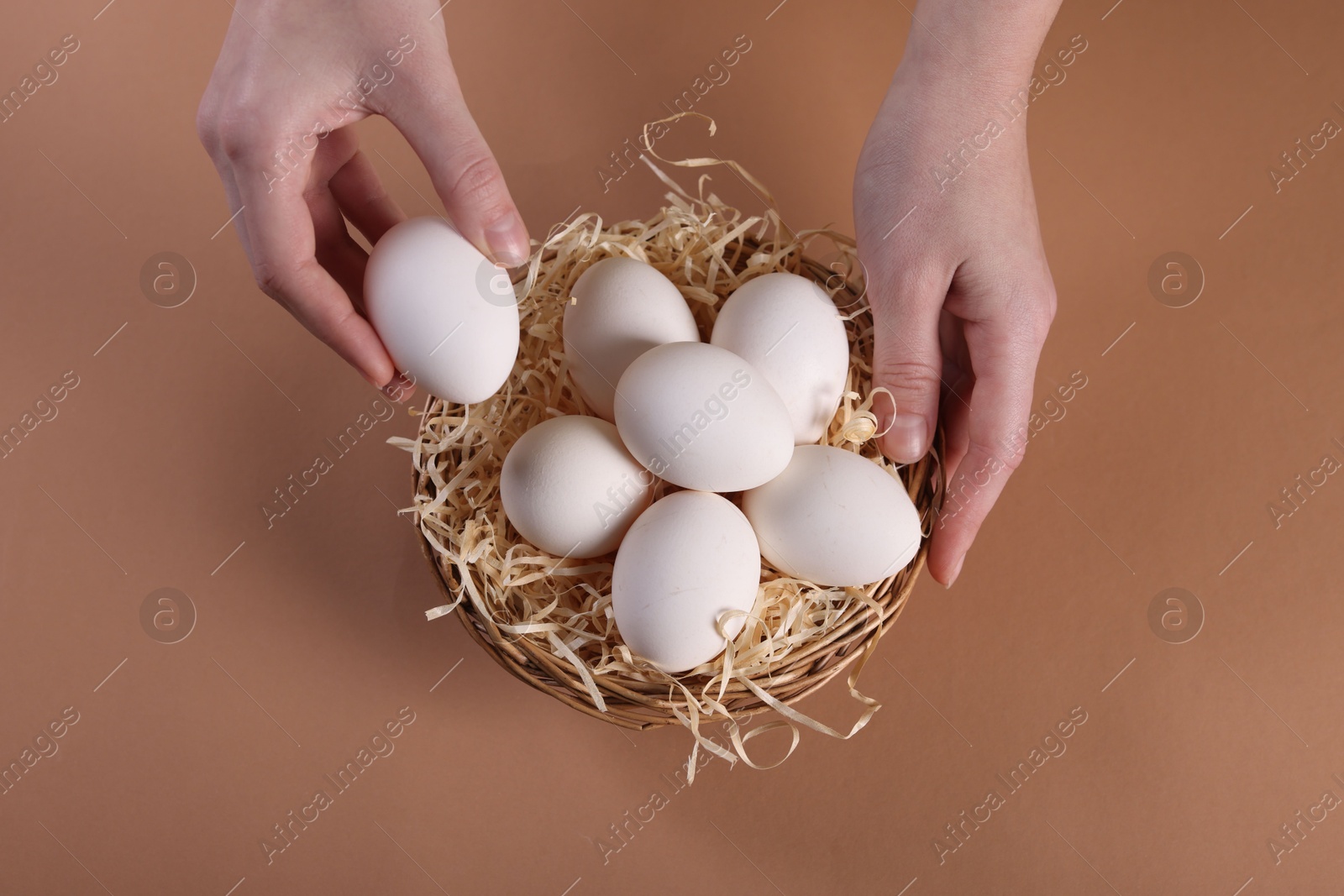 Photo of Woman with raw eggs on beige background, top view