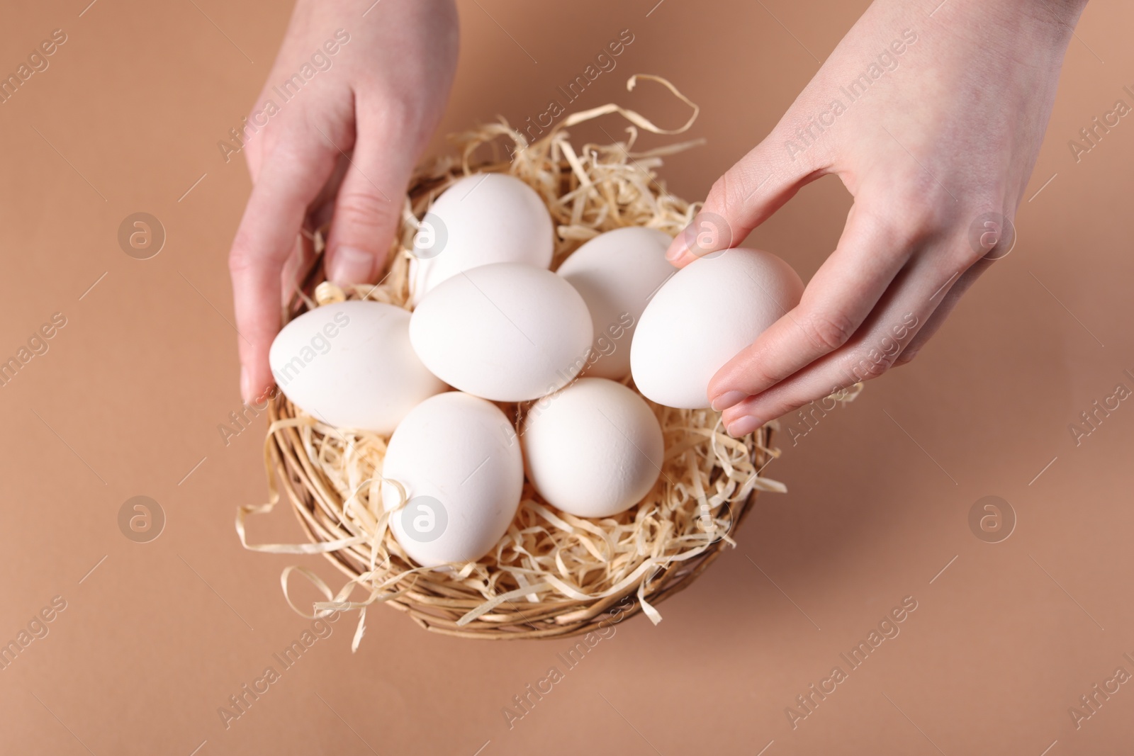 Photo of Woman with raw eggs on beige background, top view