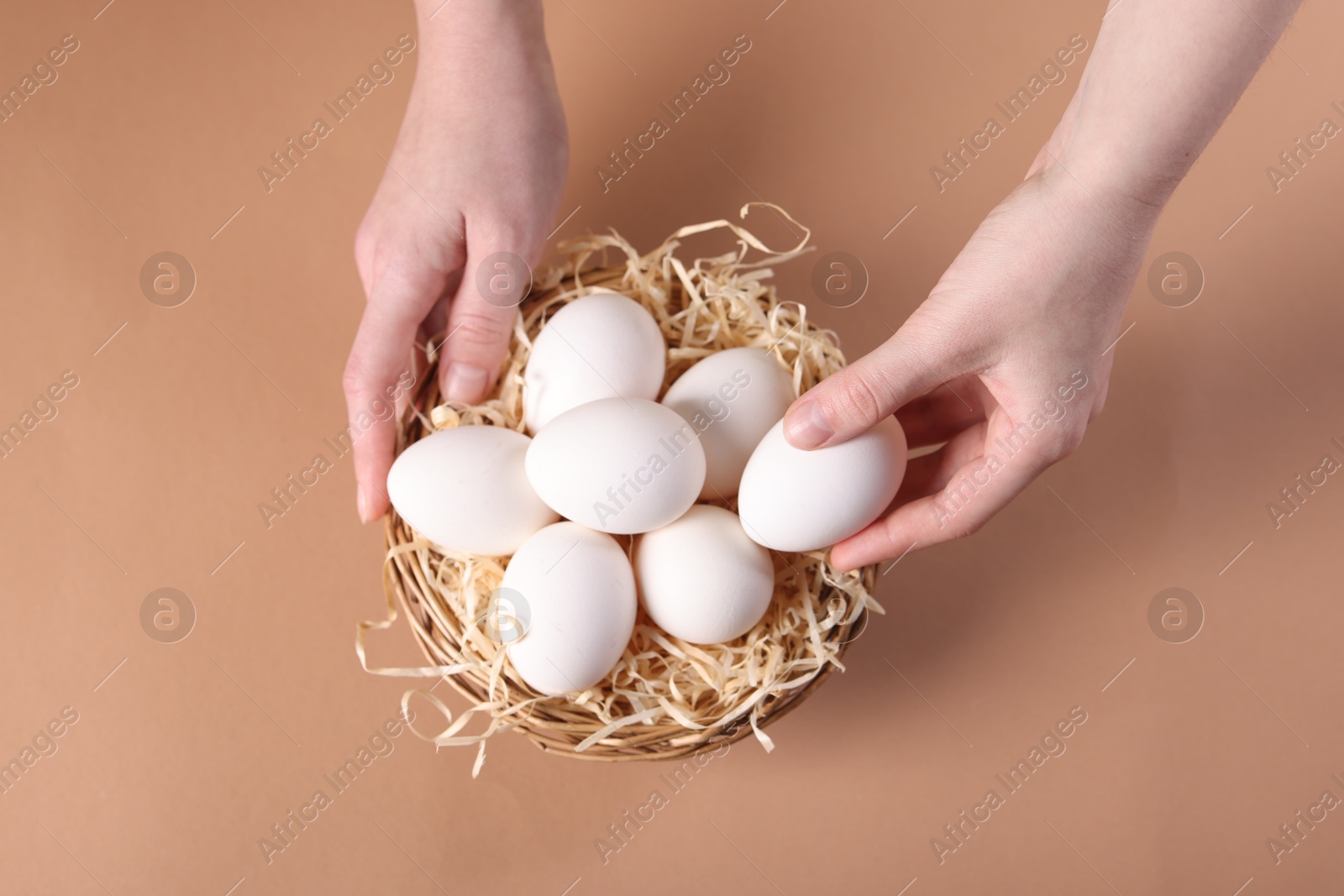 Photo of Woman with raw eggs on beige background, top view