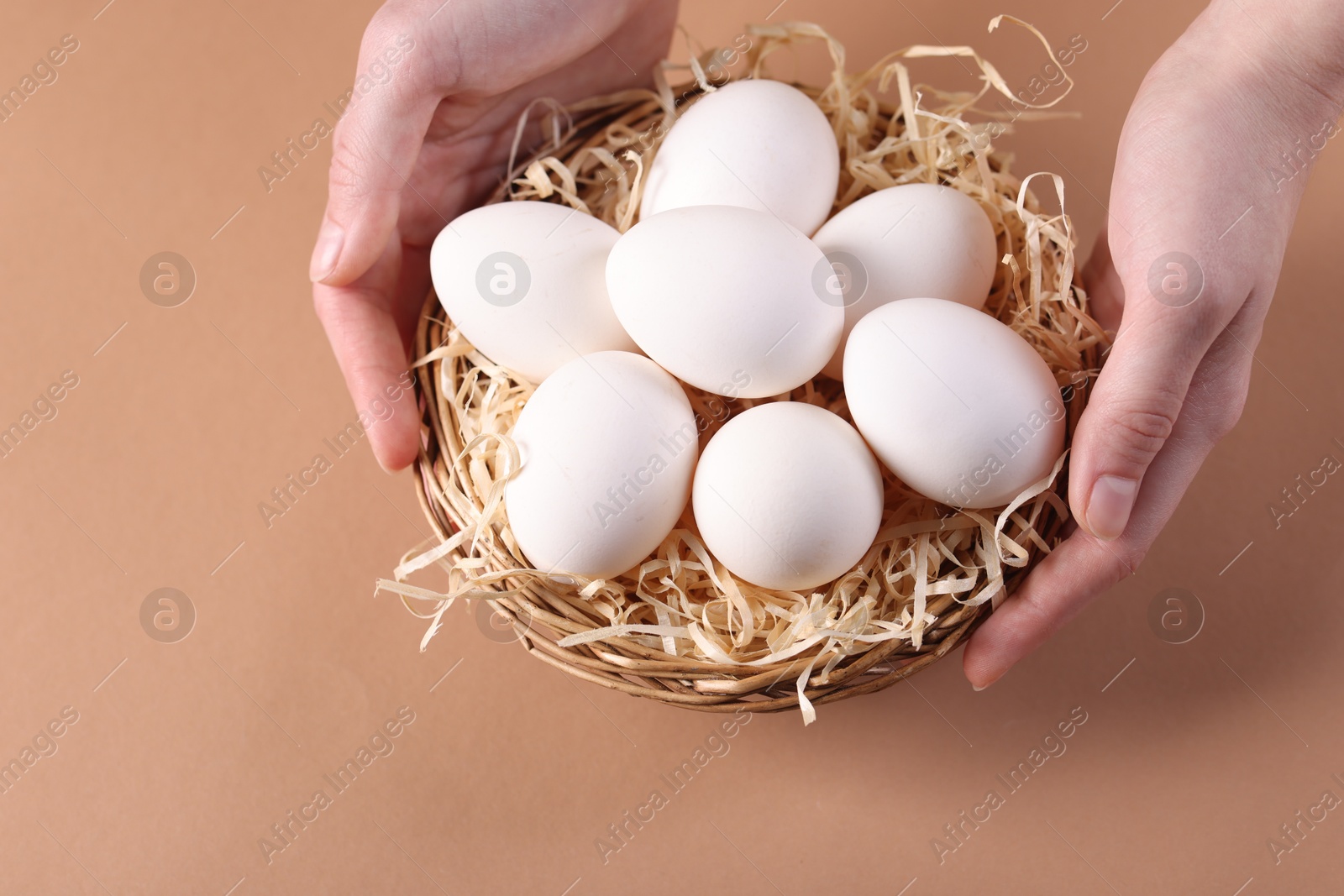 Photo of Woman with raw eggs on beige background, closeup