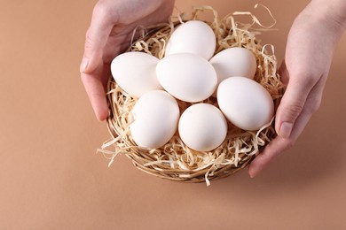 Photo of Woman with raw eggs on beige background, closeup