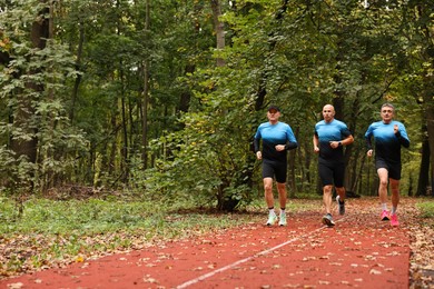 Photo of Group of athletic people running in park. Space for text