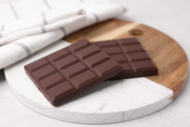 Pieces of delicious dark chocolate bar on light table, closeup