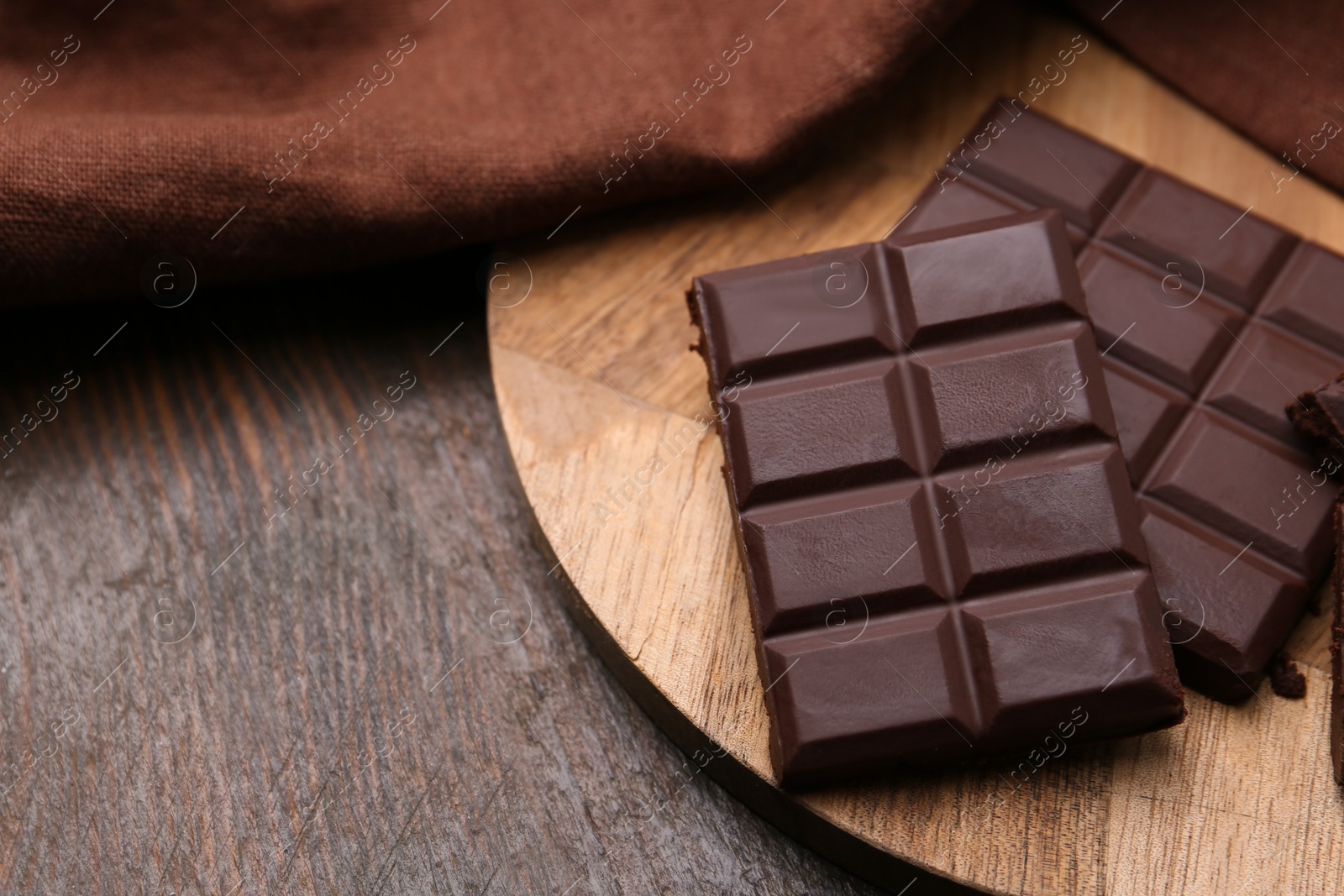 Photo of Pieces of delicious dark chocolate bar on wooden table, closeup. Space for text