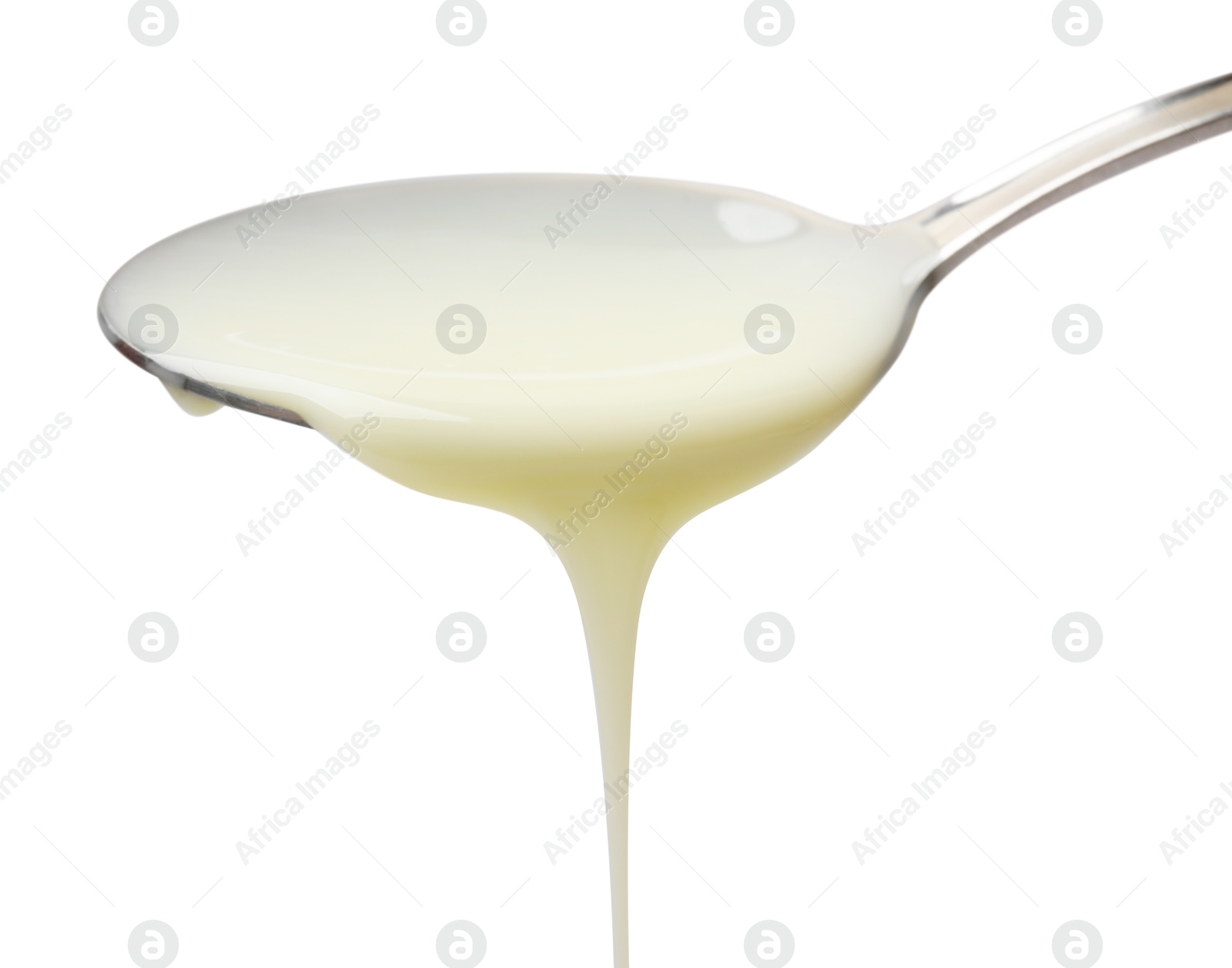 Photo of Delicious condensed milk pouring from spoon isolated on white