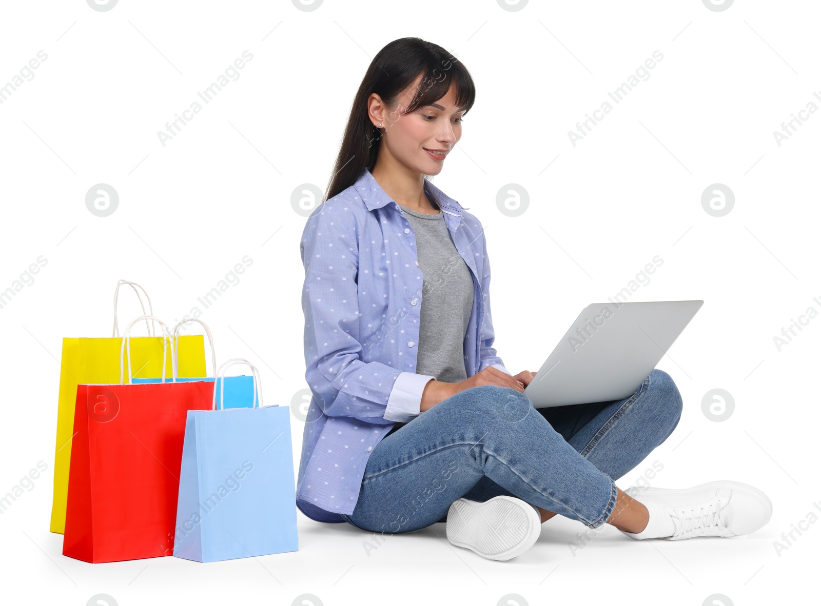 Photo of Internet shopping. Smiling woman with laptop and colorful bags on white background