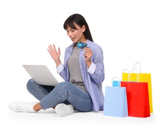 Photo of Internet shopping. Happy woman with credit card, laptop and colorful bags on white background