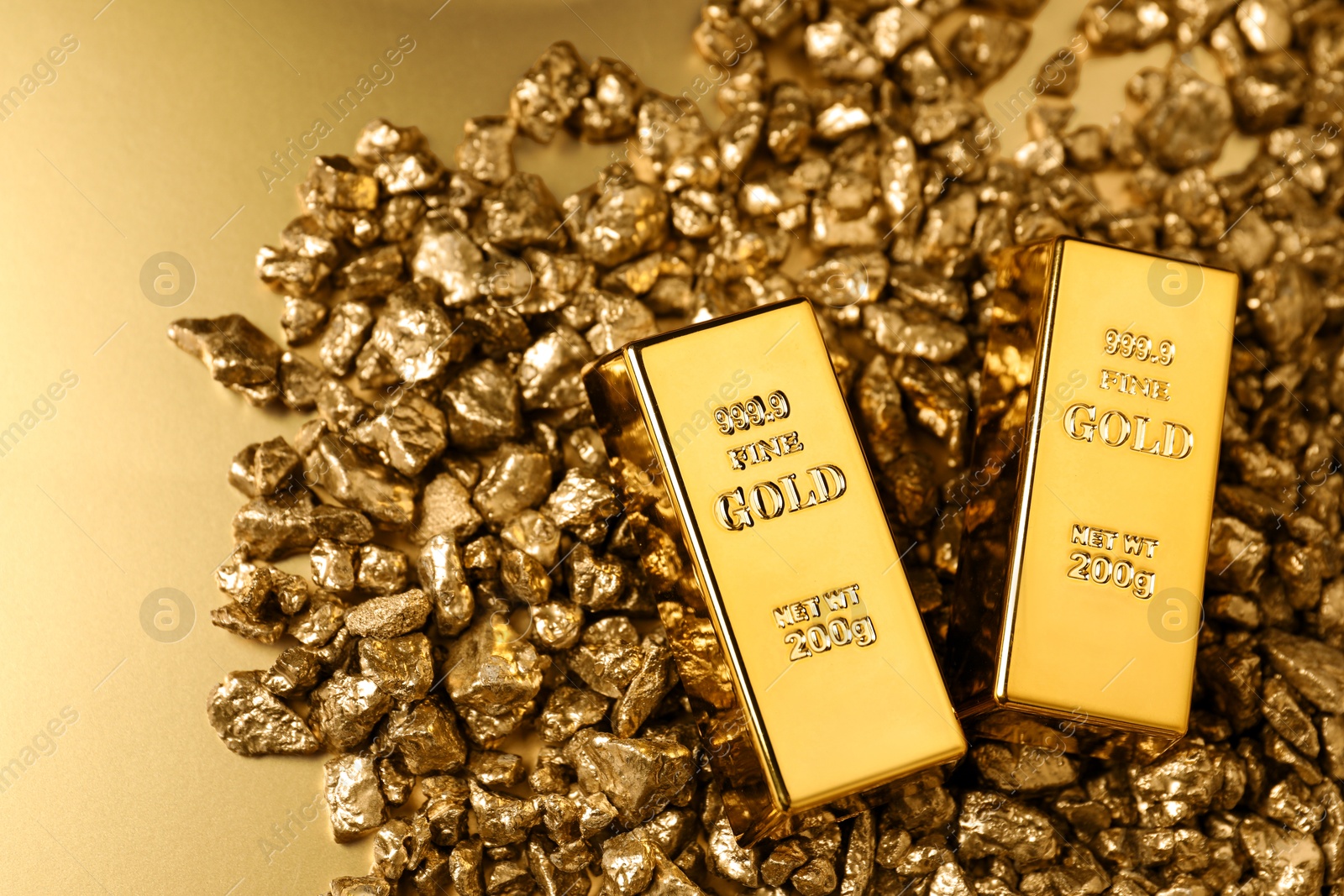 Photo of Gold nuggets and bars on shiny background, top view