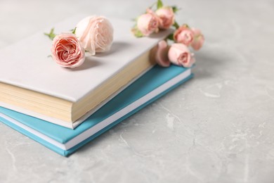 Photo of Books and beautiful rose flowers on gray marble table, closeup. Space for text