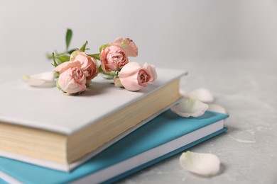 Photo of Books and beautiful rose flowers on gray marble table, closeup