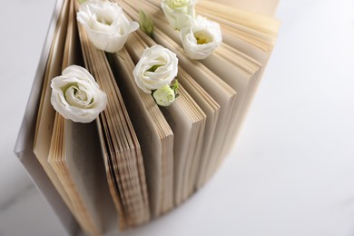 Book and beautiful eustoma flowers on white table, closeup