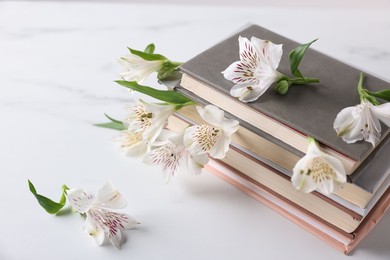 Photo of Books and beautiful alstroemeria flowers on white table, closeup