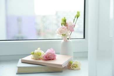 Books and beautiful flowers on window sill