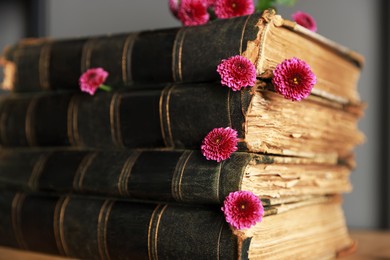 Photo of Stack of books and beautiful flowers on shelf, closeup