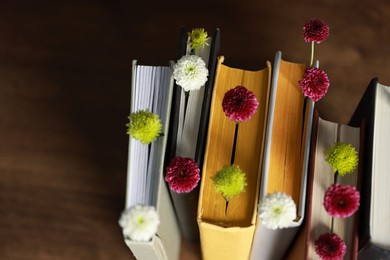 Photo of Different books with beautiful flowers on blurred background, above view. Space for text