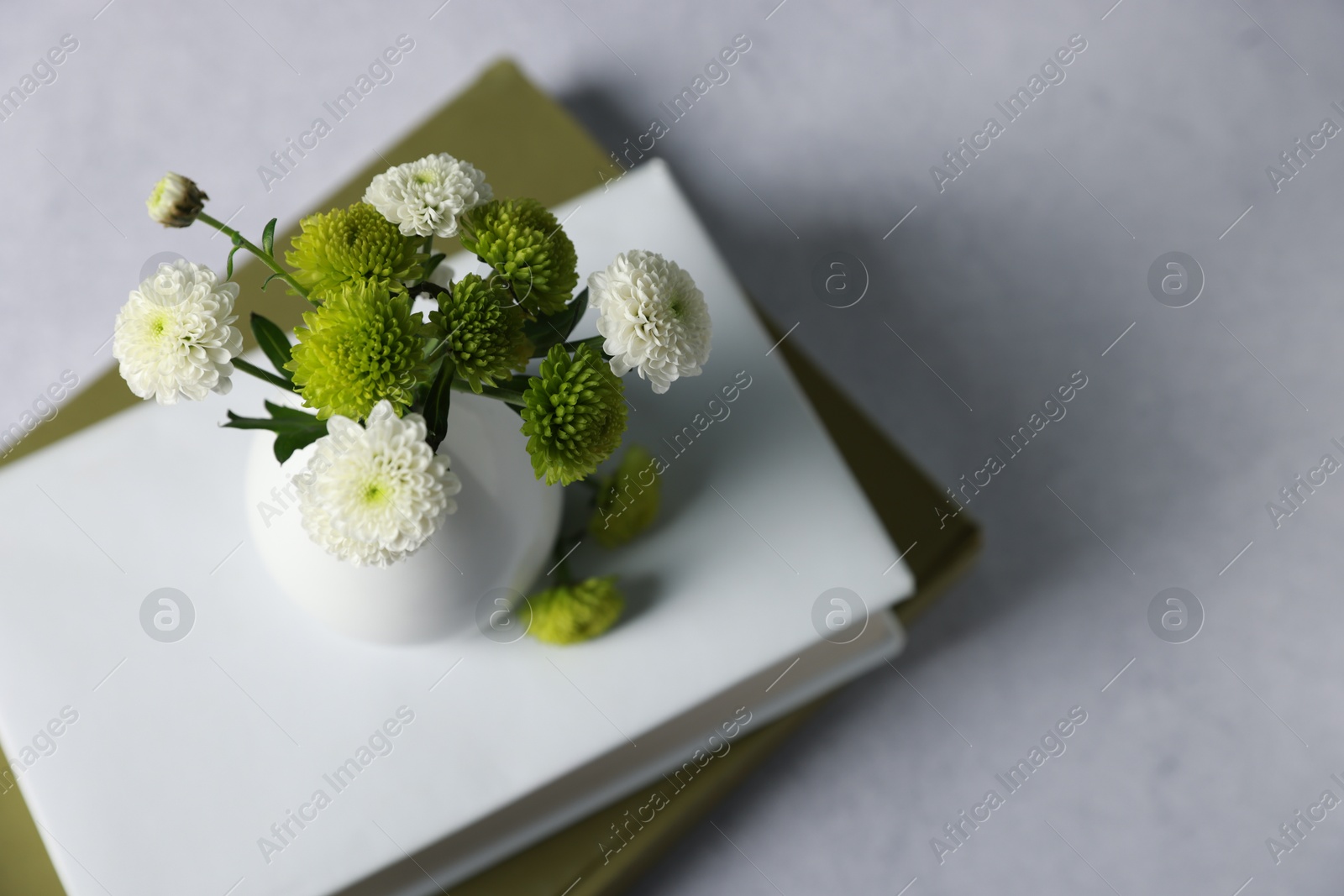 Photo of Books and vase with beautiful flowers on grey table, above view. Space for text