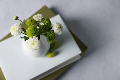 Books and vase with beautiful flowers on grey table, above view. Space for text