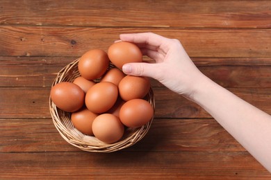 Photo of Woman with raw eggs at wooden table, top view