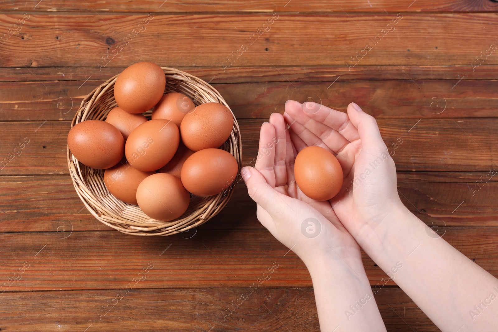 Photo of Woman with raw eggs at wooden table, top view