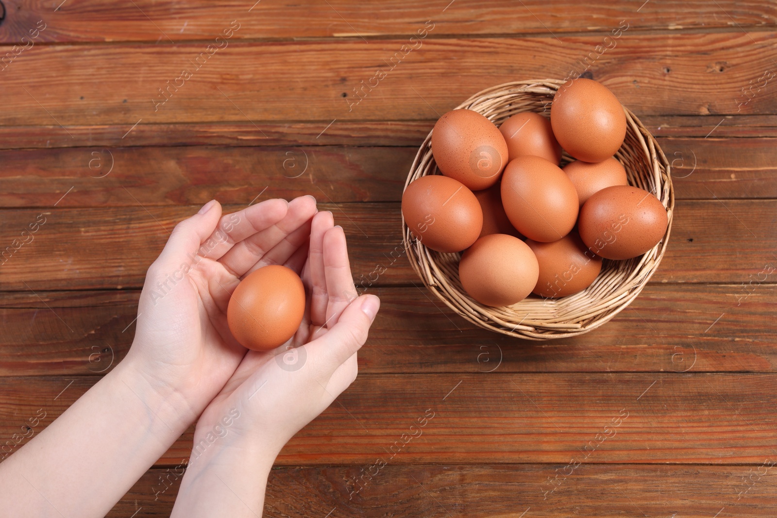 Photo of Woman with raw eggs at wooden table, top view