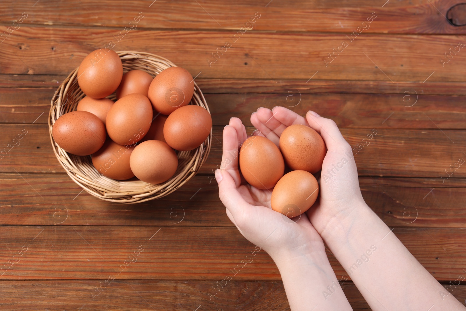 Photo of Woman with raw eggs at wooden table, top view