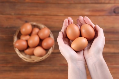 Photo of Woman with raw eggs at wooden table, closeup