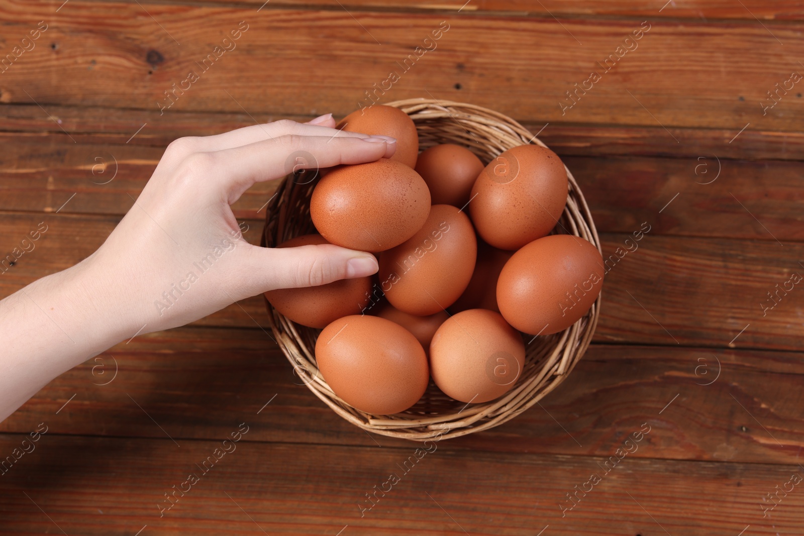 Photo of Woman with raw eggs at wooden table, top view