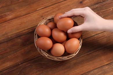 Photo of Woman with raw eggs at wooden table, closeup