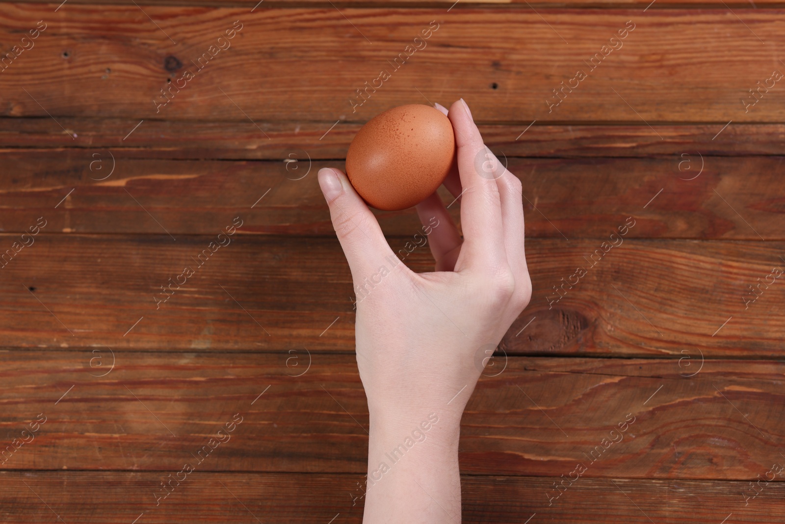 Photo of Woman with raw egg at wooden table, top view