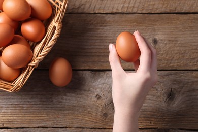 Photo of Woman with raw eggs at wooden table, top view