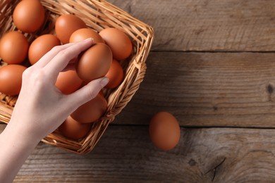 Photo of Woman with raw eggs at wooden table, top view. Space for text