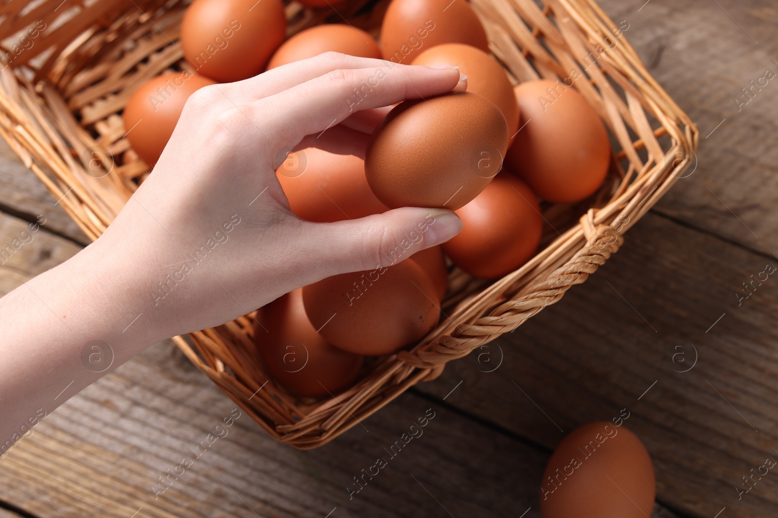 Photo of Woman with raw eggs at wooden table, closeup