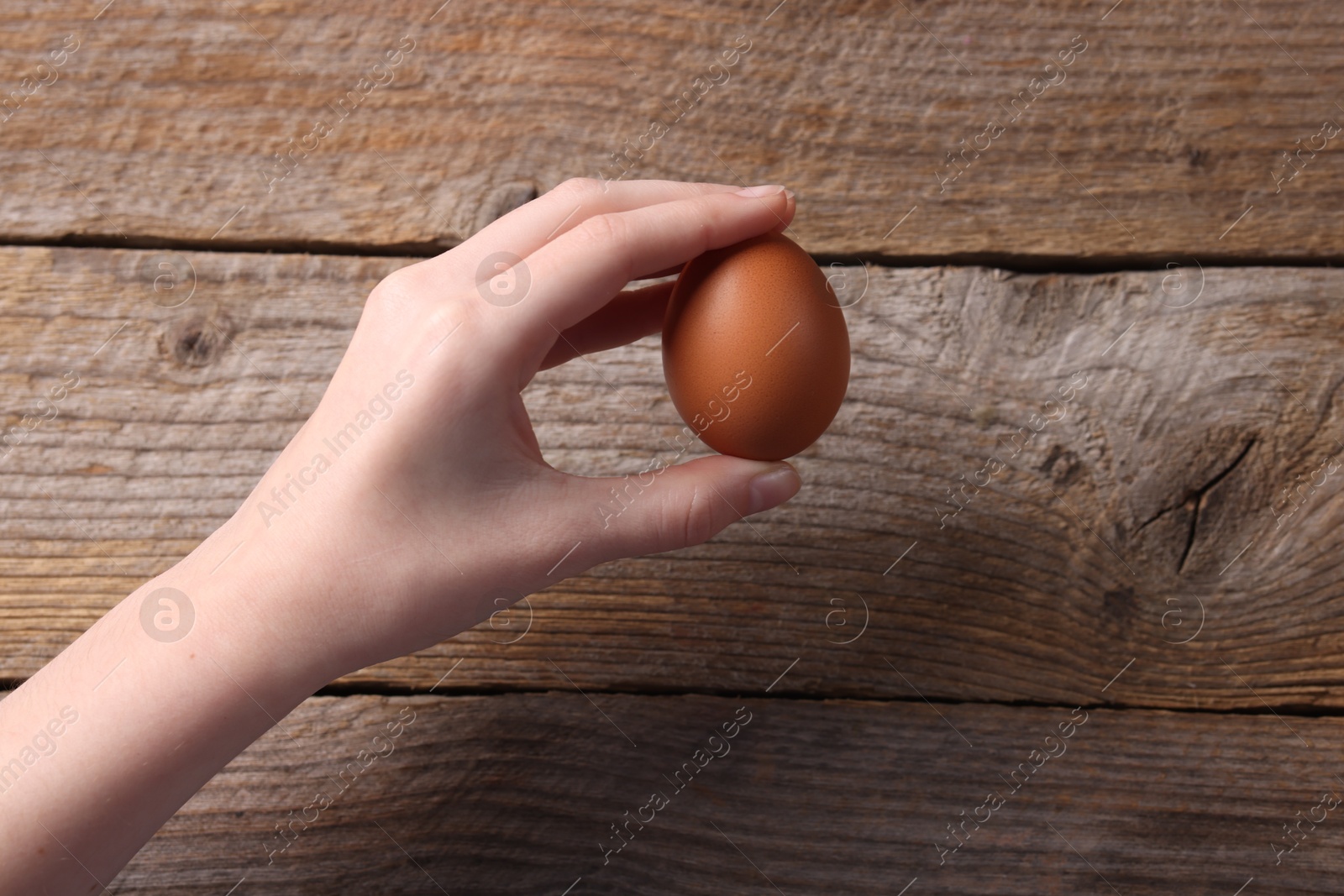 Photo of Woman with raw egg at wooden table, top view