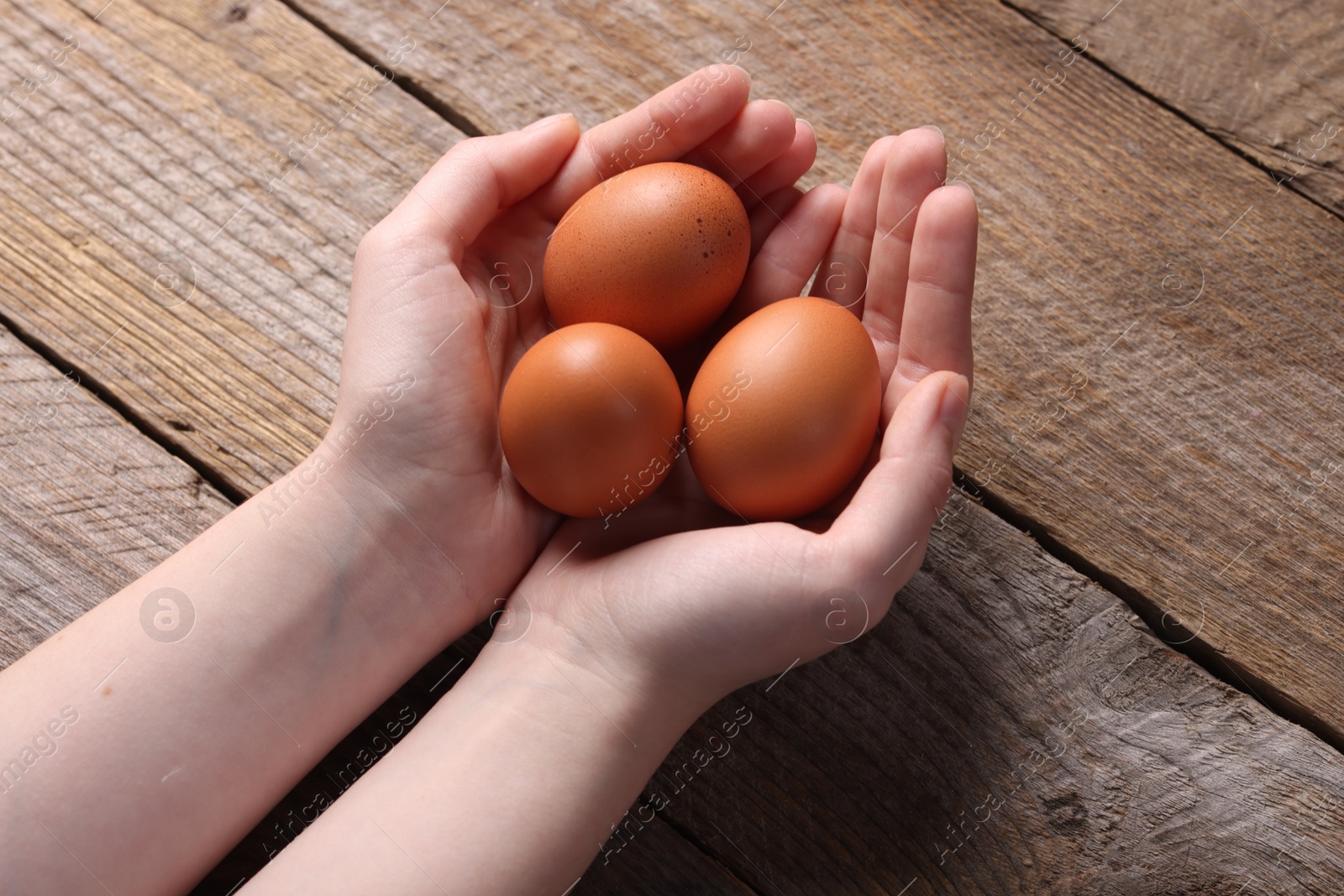 Photo of Woman with raw eggs at wooden table, closeup