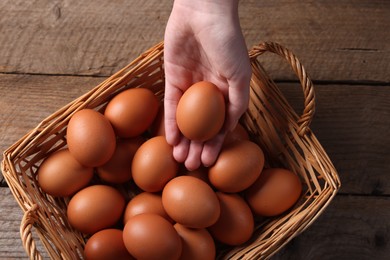 Photo of Woman with raw eggs at wooden table, top view