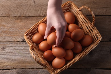 Photo of Woman with raw eggs at wooden table, top view