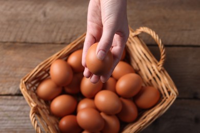 Photo of Woman with raw eggs at wooden table, top view