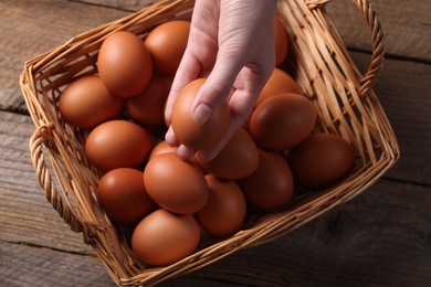 Photo of Woman with raw eggs at wooden table, top view