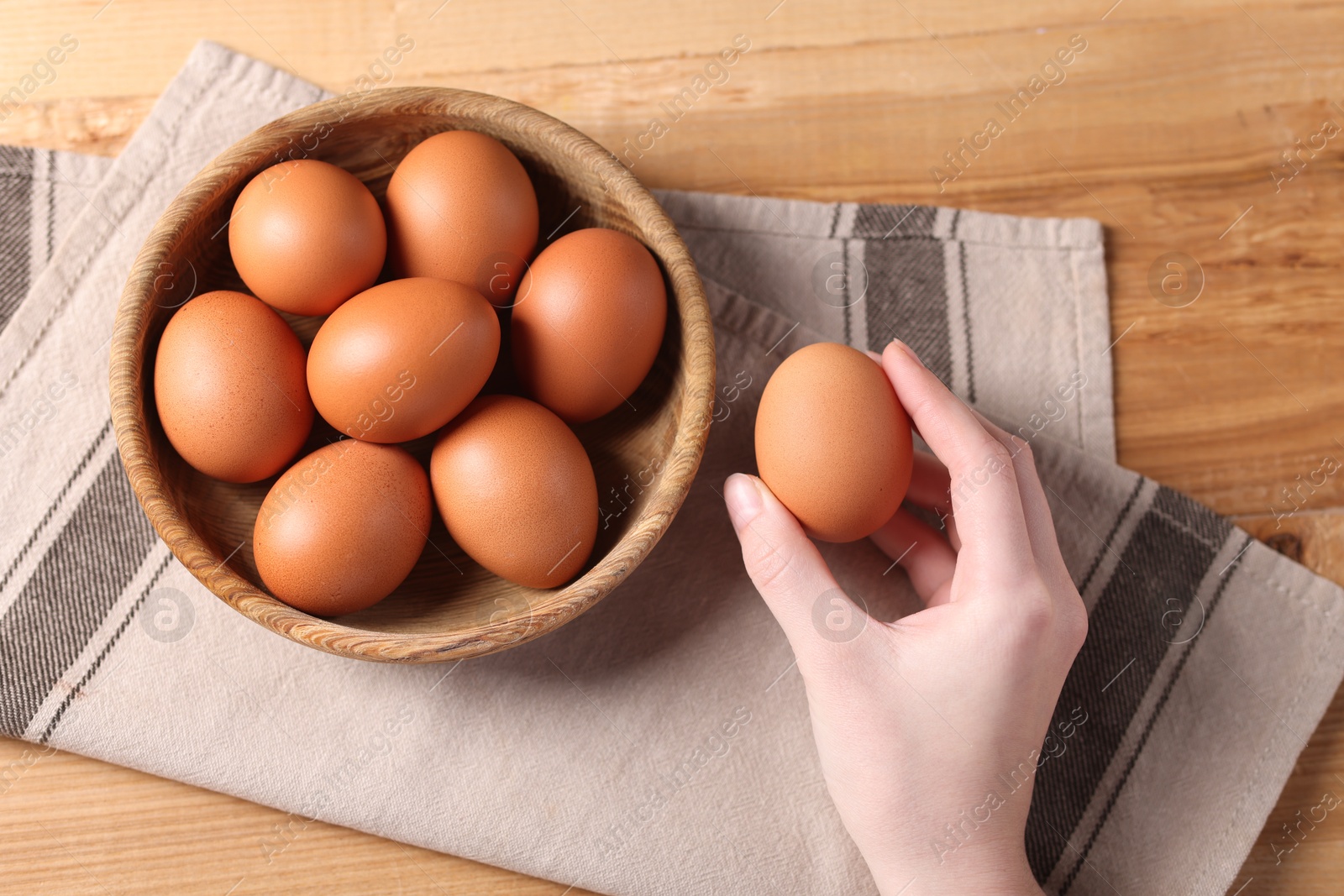 Photo of Woman with raw eggs at wooden table, top view