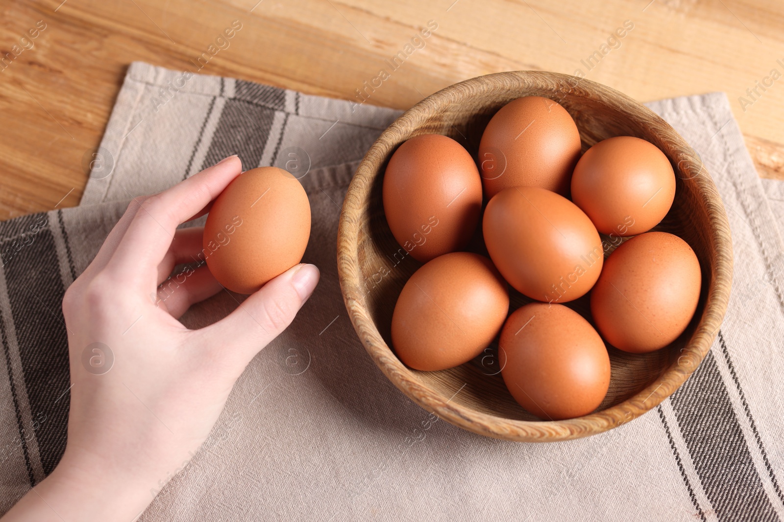 Photo of Woman with raw eggs at wooden table, top view