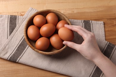 Photo of Woman with raw eggs at wooden table, above view