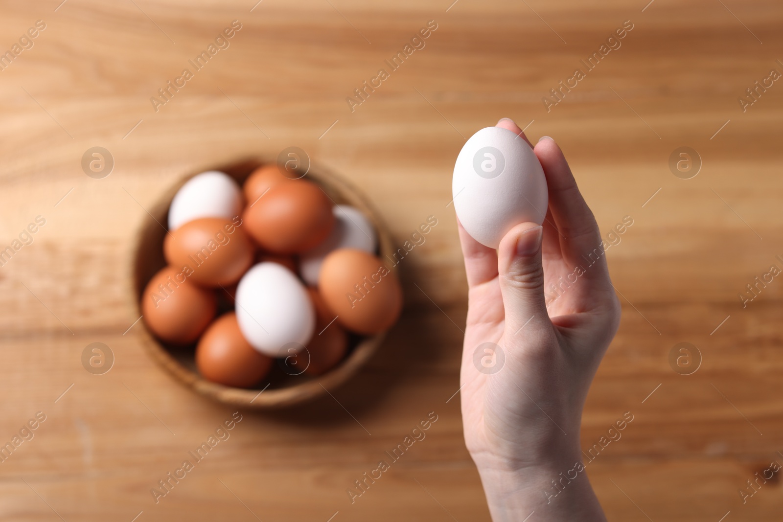 Photo of Woman with raw eggs at wooden table, top view