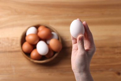 Photo of Woman with raw eggs at wooden table, top view